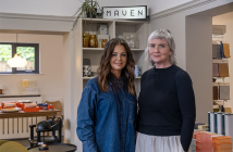 Sarah and Patricia stand in front of a Maven sign inside the Maven shop