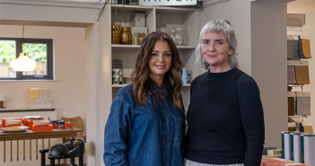 Sarah and Patricia stand in front of a Maven sign inside the Maven shop